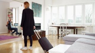 Symbolbild: Eine Frau betritt das Wohnzimmer einer Ferienwohnung mit dem Rollkoffer. (Quelle: dpa/Holz)