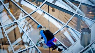 Symbolbild: Ein Mitarbeiter reinigt am 18.10.2013 die Scheiben in der Glaskuppel des Reichstags in Berlin über dem Plenarsaal vor dem Bundesadler. (Quelle: dpa-Bildfunk/Kay Nietfeld)