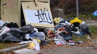 Archivbild: Alte Kleidung liegt neben dem Container auf dem Boden. (Quelle: dpa/Simon)