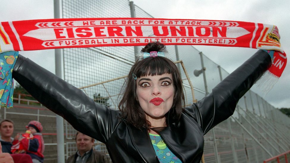Die Pop-Sängerin Nina Hagen hält am Montag (24.8.98) in Berlin einen Fan-Schal des Fußball-Regionalligaklubs 1. FC Union über ihren Kopf. (Quelle: Picture Alliance/Peer Grimm)