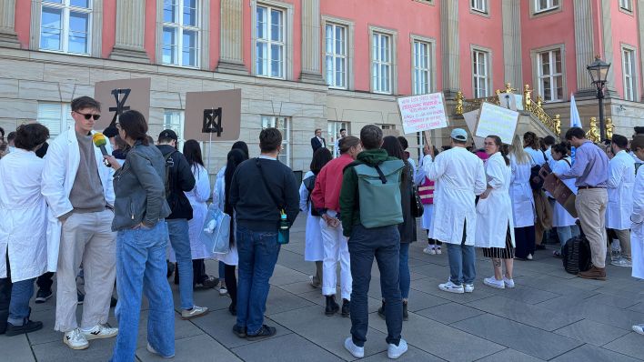 Dutzende Studentinnen und Studenten der Medizinischen Hochschule Brandenburg - Theodor Fontane (MHB) protestieren vor dem Landtag in Potsdam gegen Kürzungen im geplanten Doppelhaushalt des Landes. (Quelle: dpa/Riegen) Dutzende Studentinnen und Studenten der Medizinischen Hochschule Brandenburg - Theodor Fontane (MHB) protestieren vor dem Landtag in Potsdam gegen Kürzungen im geplanten Doppelhaushalt des Landes. (Quelle: dpa/Riegen)