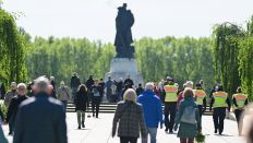 Besucher und Polizeibeamte gehen am 08.05.2025 im sowjetischen Sowjetischen Ehrenmal Treptow in Richtung der haushohen Statue eines sowjetischen Soldaten. (Quelle: dpa-Bildfunk/Sebastian Gollnow)