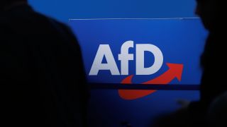 ARCHIV - 28.07.2023, Sachsen-Anhalt, Magdeburg: Delegierte gehen vor dem Parteilogo bei dem AfD-Bundesparteitag in Magdeburg.