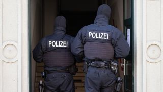 Archivbild: Polizisten stehen während einer Razzia gegen mutmaßliche Rechtsextreme in einem Hauseingang. (Quelle: dpa/Kahnert)